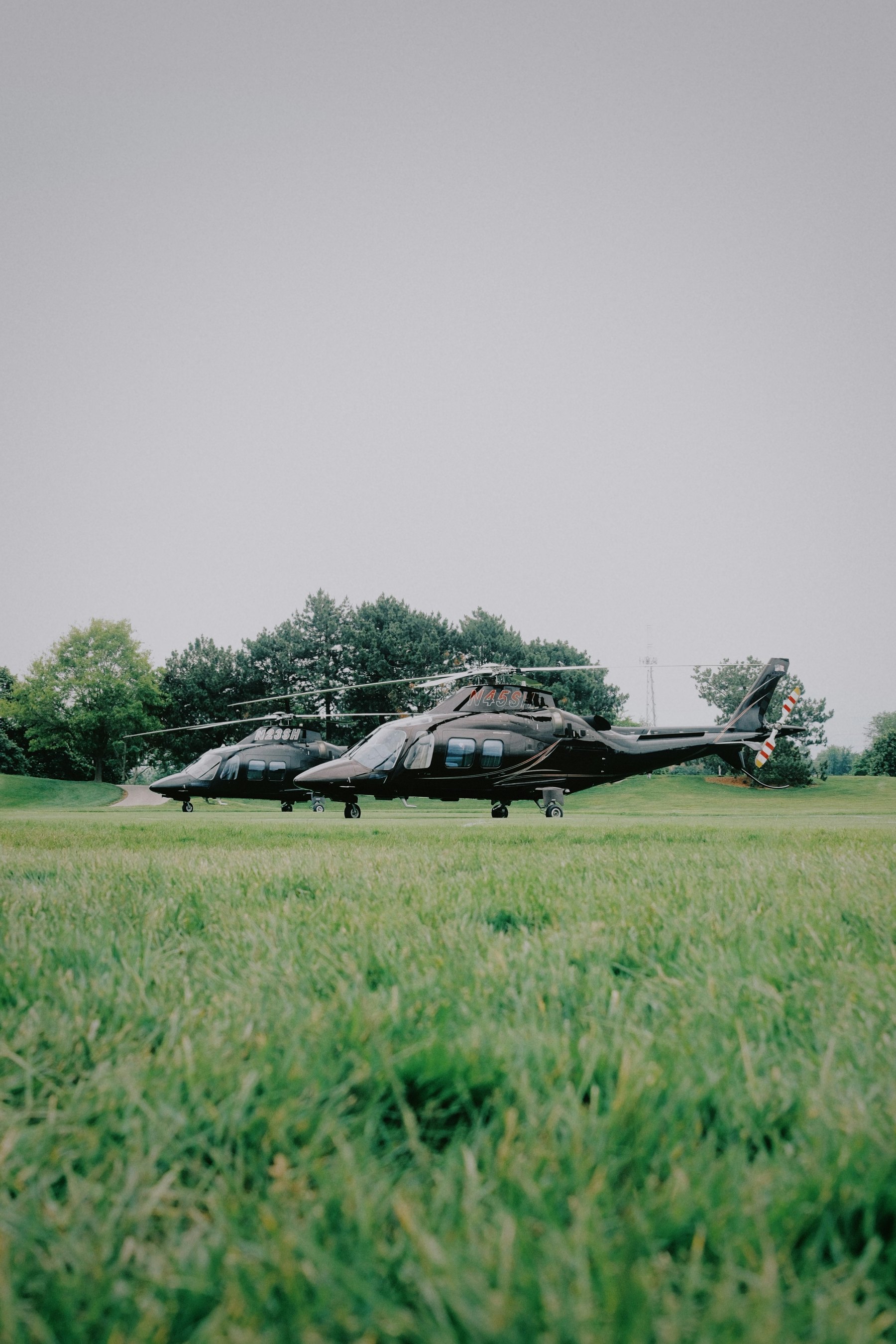 Private helicopters parked on a grass airfield